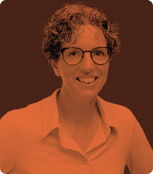 Person with short curly hair and glasses smiling, wearing a collared shirt with a halftone orange effect.