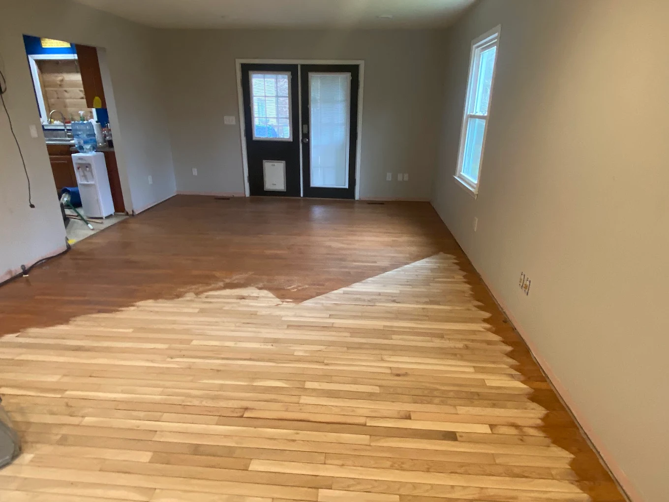 Hardwood floors in the middle of being sanded by A-max flooring in Greenville, SC. Half of the floor has old finish on it, and the other half is freshly sanded.