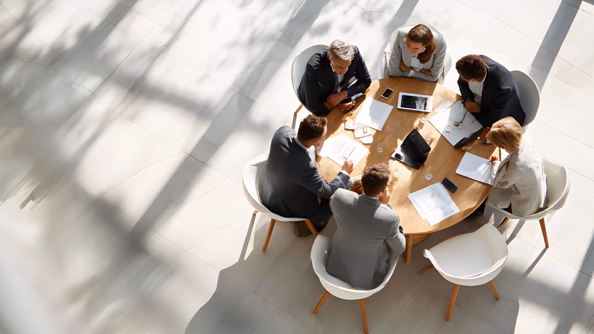 Professionals seated around a round table in a meeting, seen from an overhead view, discussing strategy and collaborating