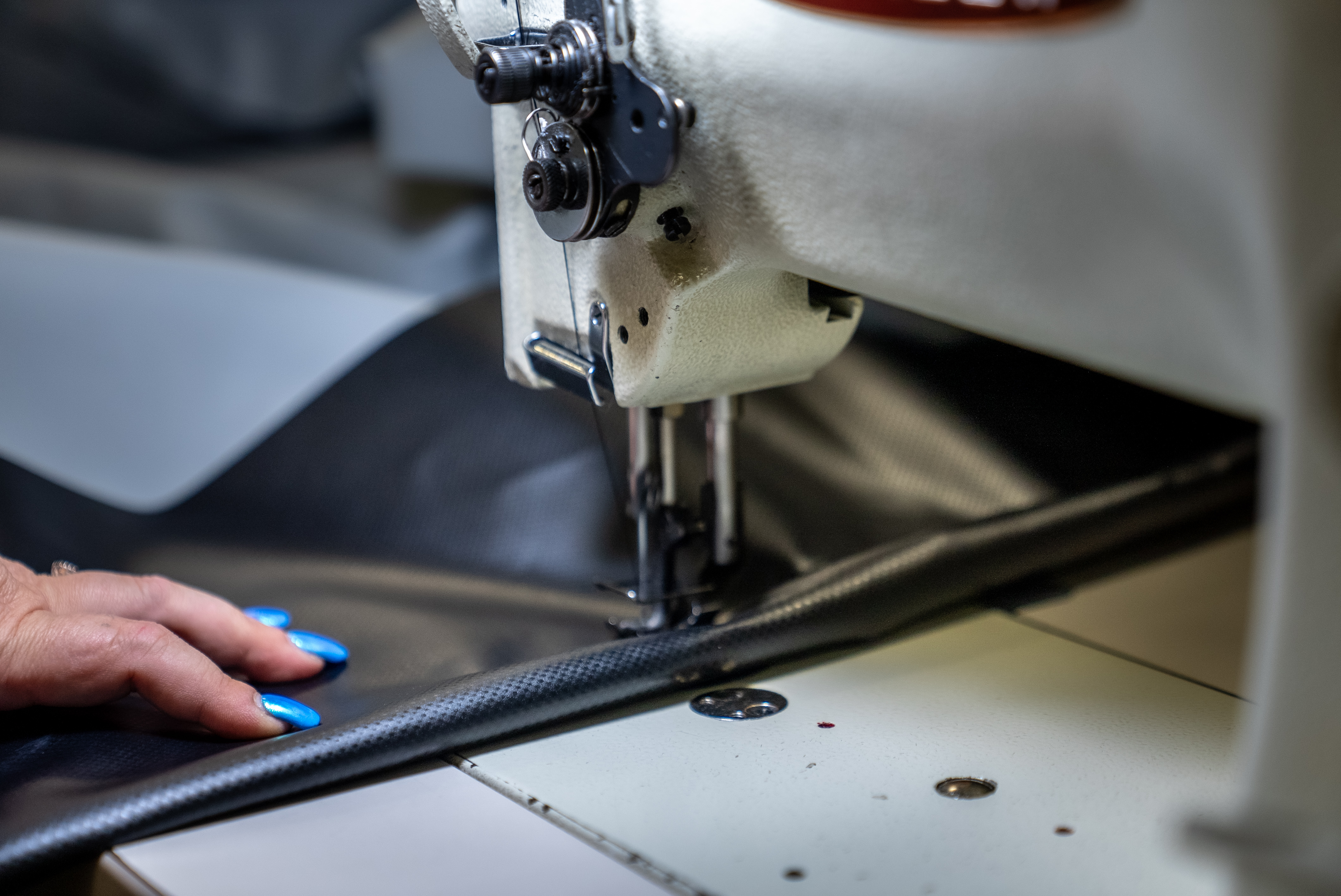 A seamstress hand-sewing a boat cover at the Marine Concepts shop