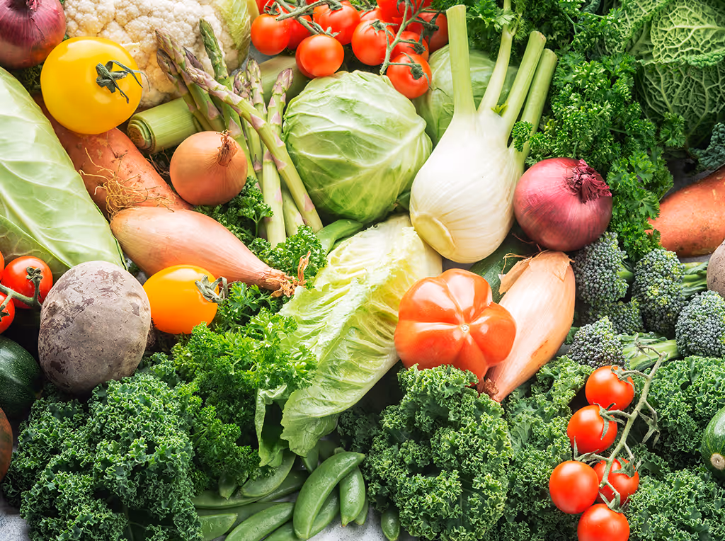 Assortment of fresh vegetables including kale, tomatoes, cabbage, asparagus, onions, fennel, and snap peas.