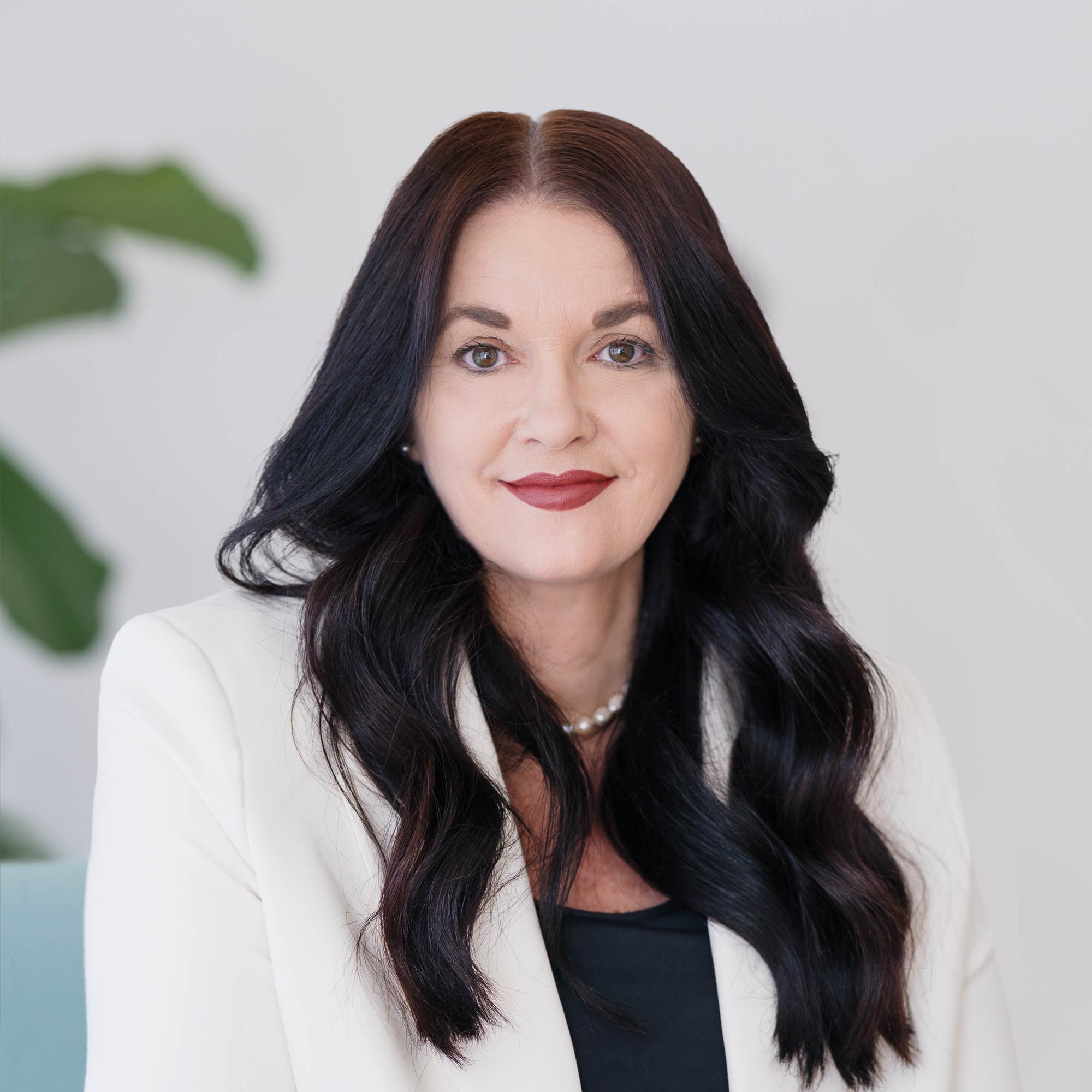 Creative Director of BrandOps Janine Morice in white corporate jacket with black top and long wavy dark hair