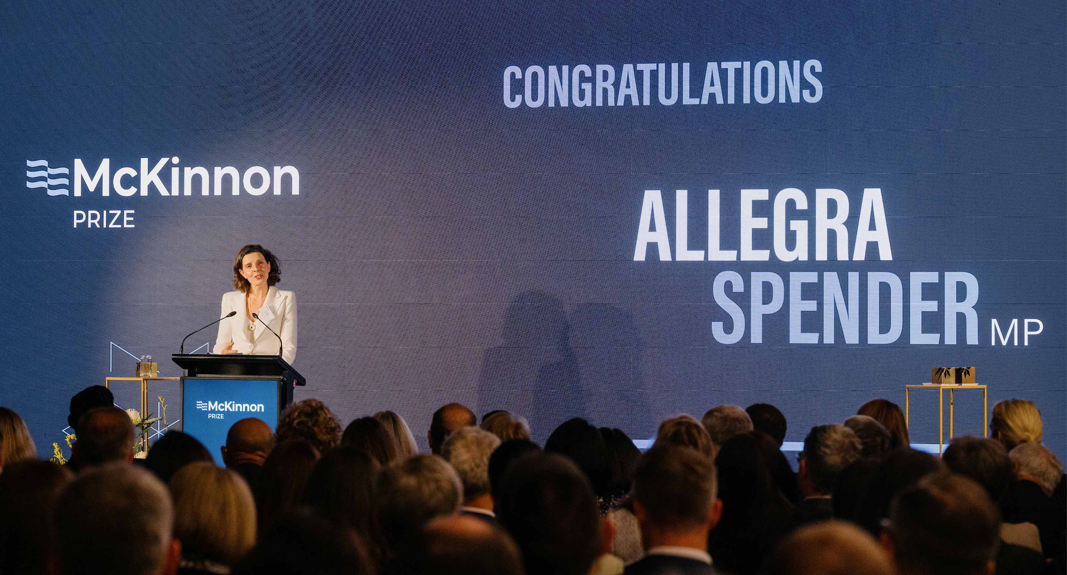 Photo from the McKinnon Prize event 2025. Allegra Spender accepting her award on stage.