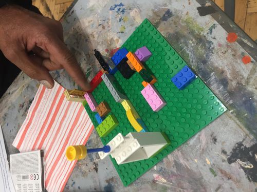 A lego model with a finger pointing at one part