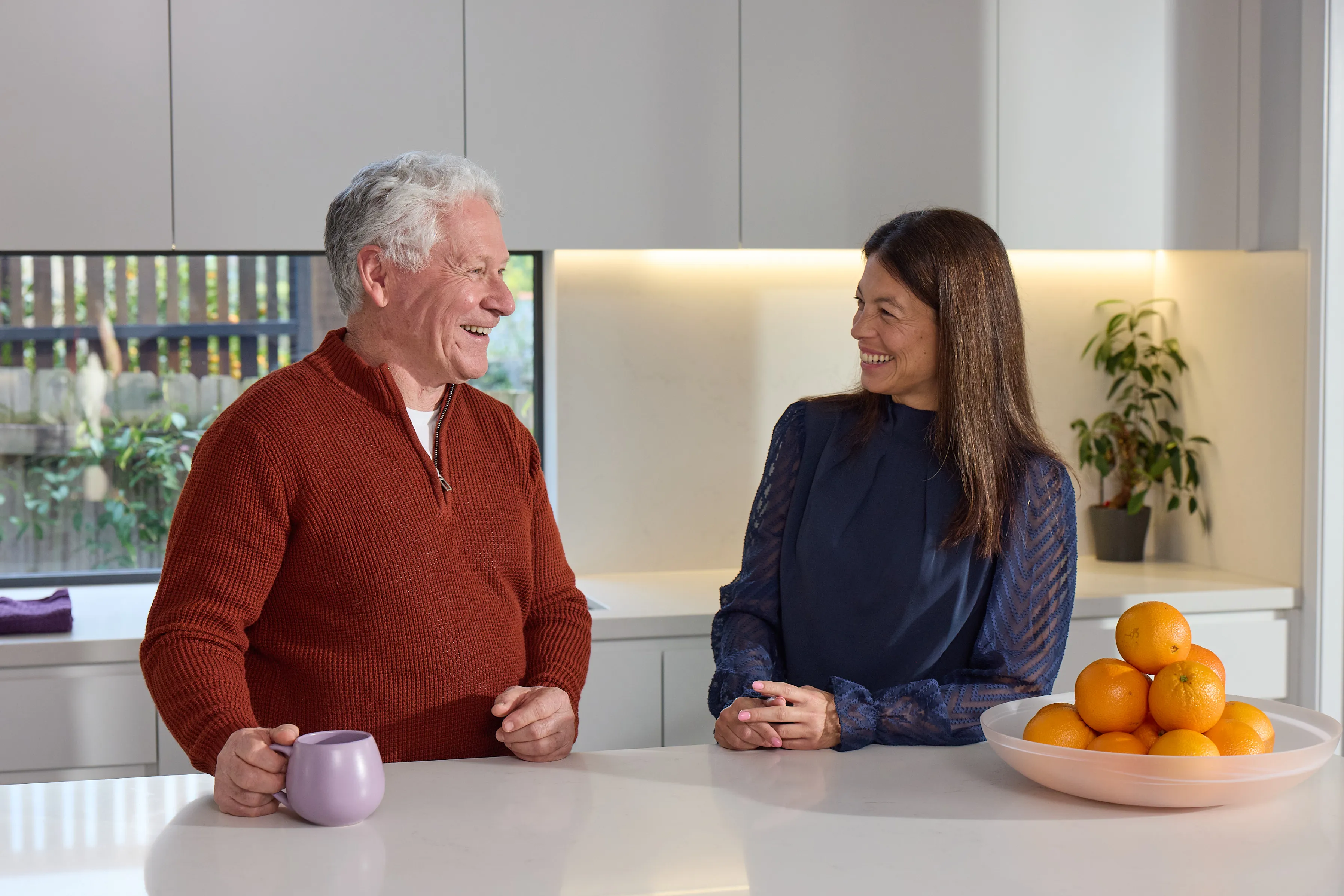 Older man and woman chatting in their kitchen at home, where Updoc connects Australians with an online doctor