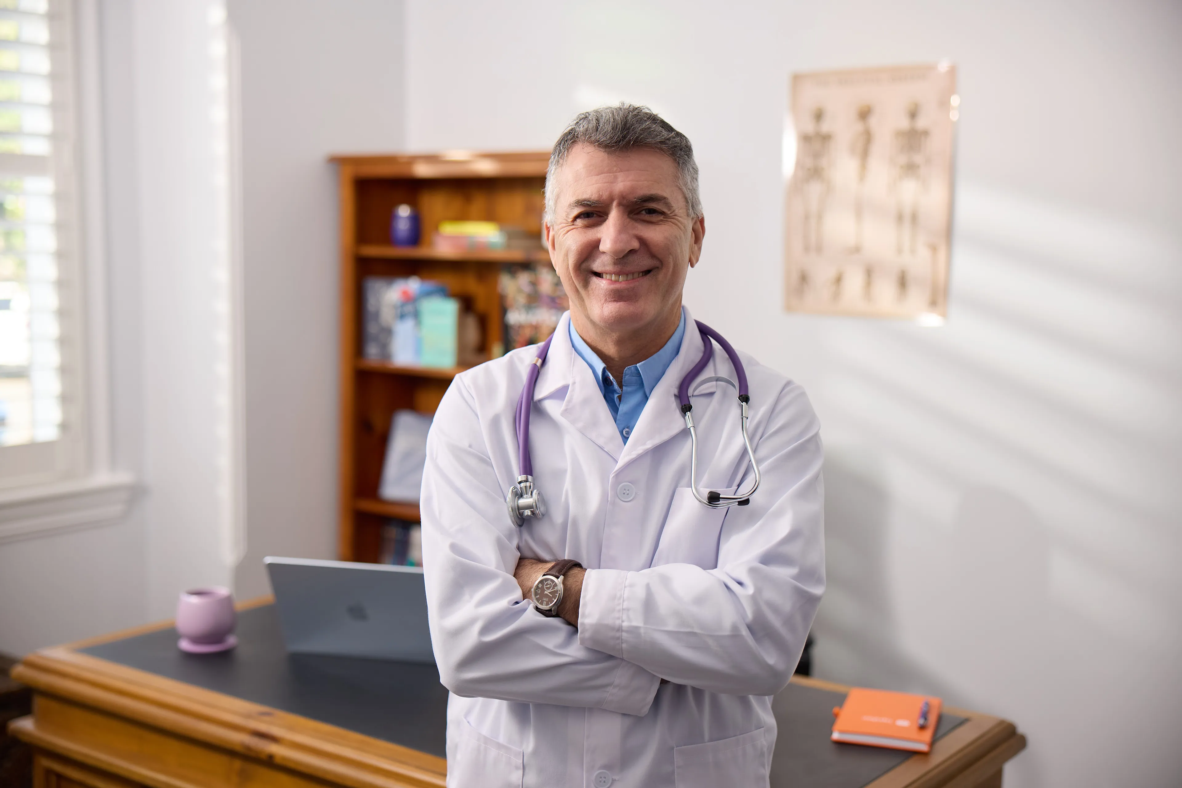 Smiling male Partner Doctor with a stethoscope in his consulting room, ready to discuss an ENT referral
