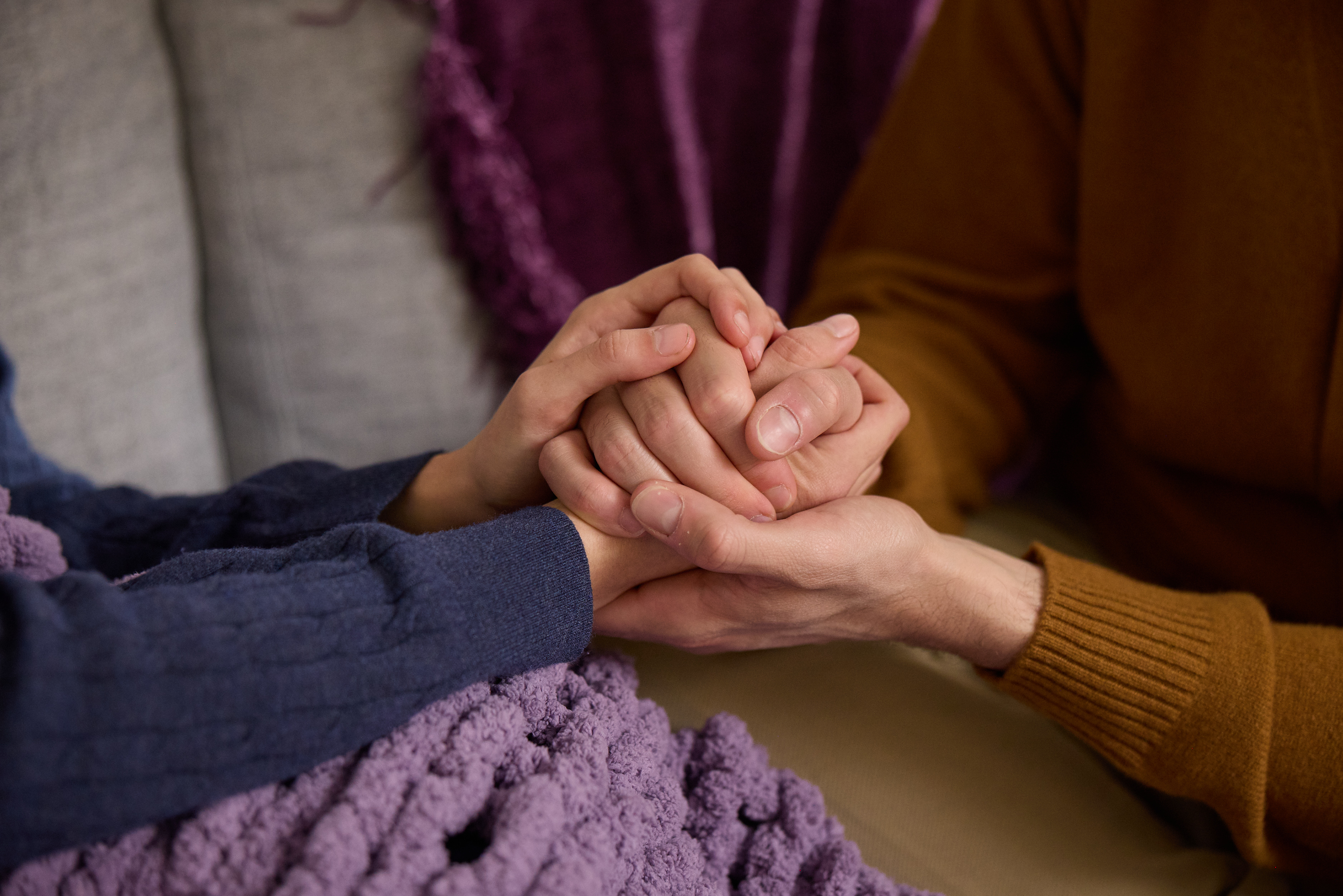 Two people holding hands on the couch for support before an IVF telehealth appointment