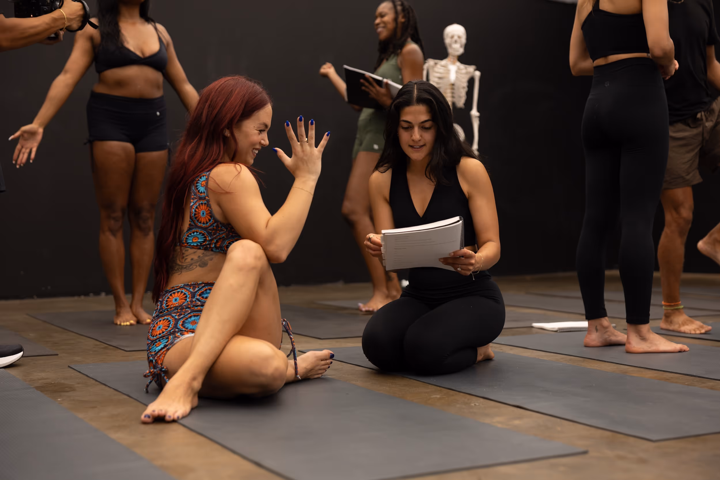Diverse group in yoga studio with skeleton, practicing and taking notes