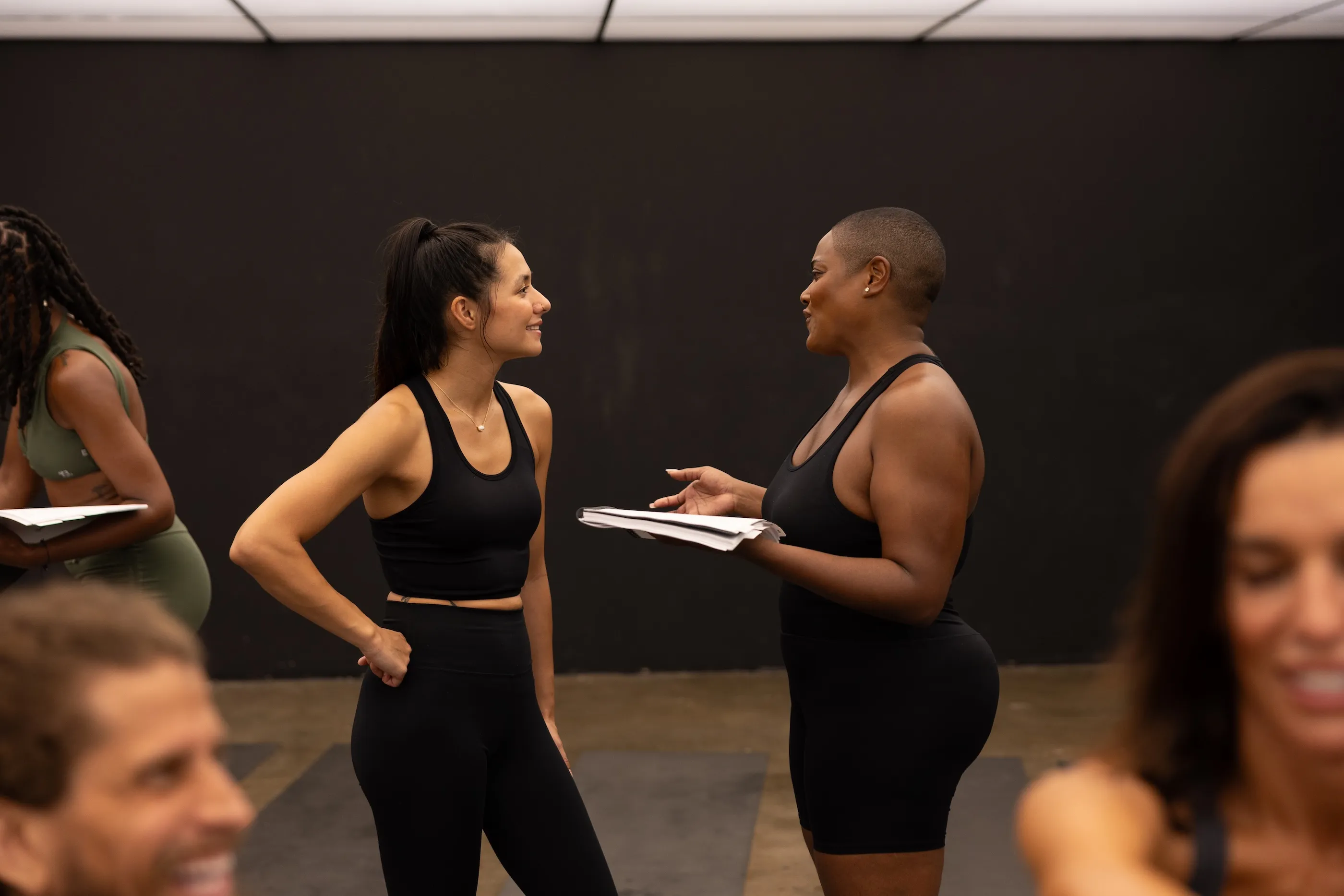Two women in workout clothes talking and smiling in fitness studio