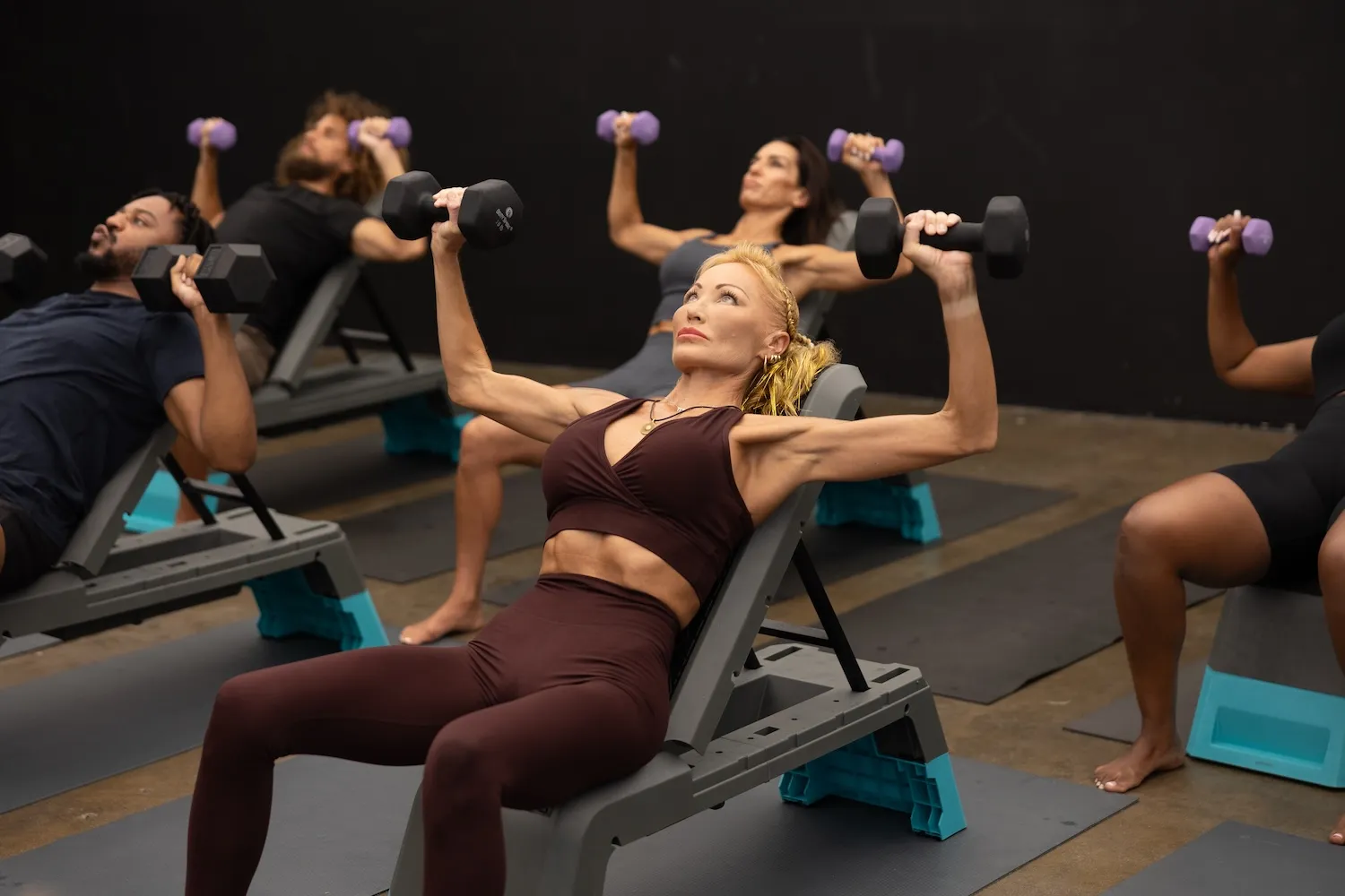 Group fitness class doing dumbbell chest press on exercise benches