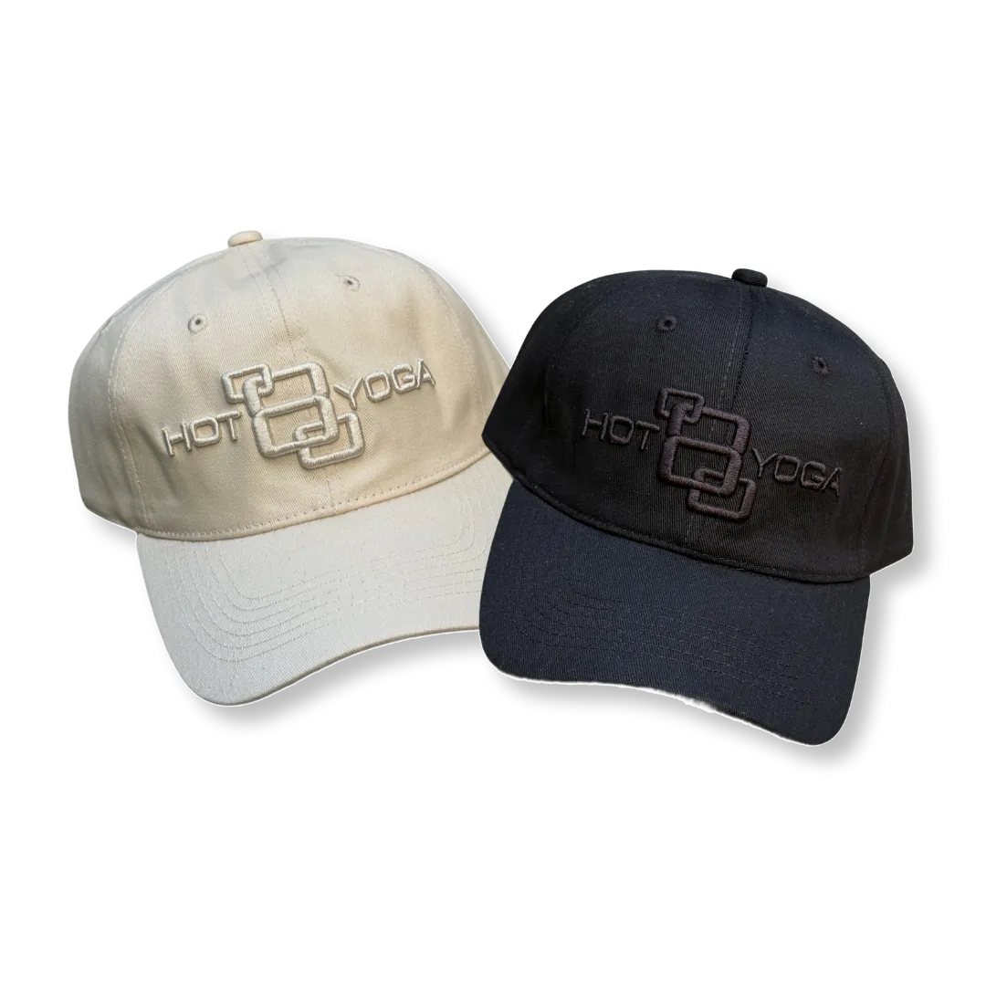 Two embroidered baseball caps: one cream-colored and one black with Hot 8 Yoga logo