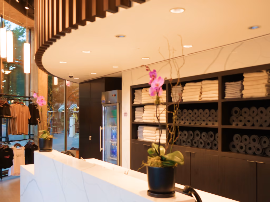 Modern spa reception with white marble desk, towel shelves, pink orchids, and elegant decor
