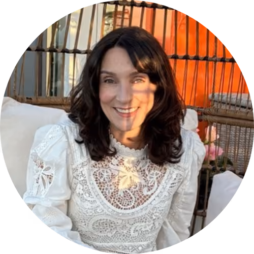 Smiling woman with dark hair wearing a white lace top.