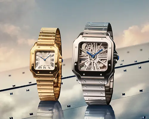 Gold and silver Cartier wristwatches with square faces and blue hands displayed on reflective surface.