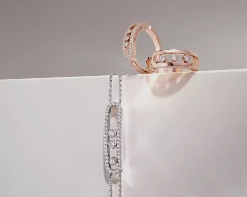 Rose gold rings with diamonds and a silver bracelet with diamonds on a white surface.