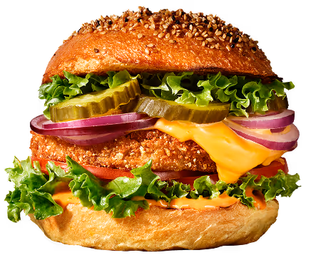 Vegaburger met sla, tomaat, augurken, rode ui, gesmolten cheddar kaas en een gepaneerd burgertje in een sesambroodje