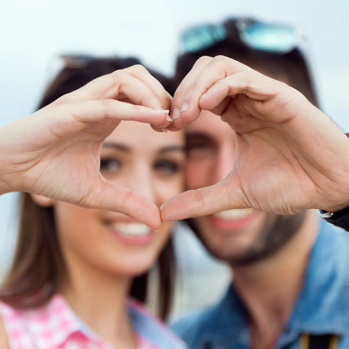 Un couple forme un cœur avec ses mains