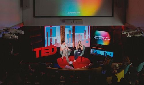 Two hosts on stage in the TED World Theater