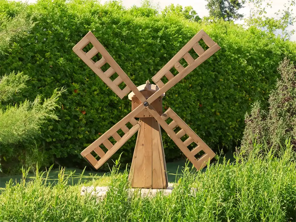 A handmade wooden windmill shown in a garden situ