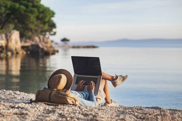 Image of a digital nomad working in their laptop from a beach