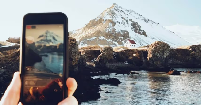 person taking a photo of a mountain on their cell phone