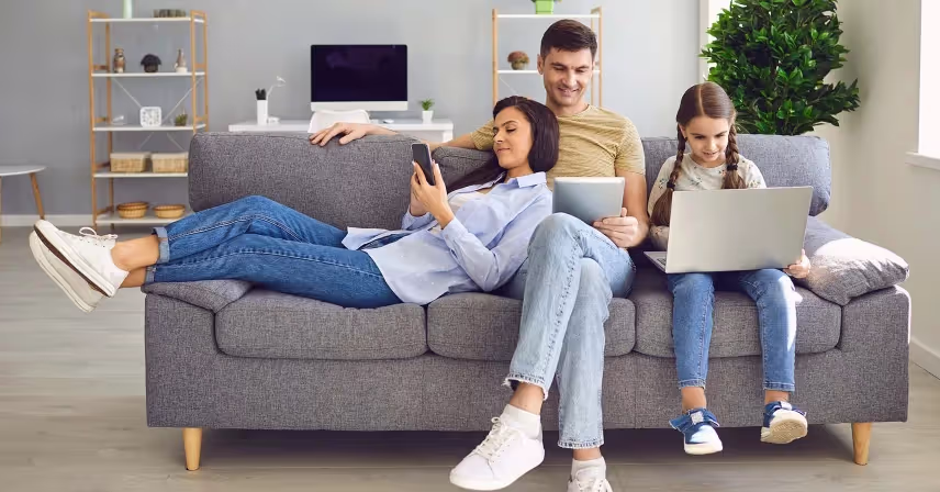 a group of people sitting on a couch and using smart phones