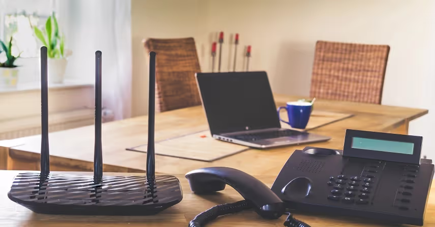 a desk with a laptop, phone, and internet router