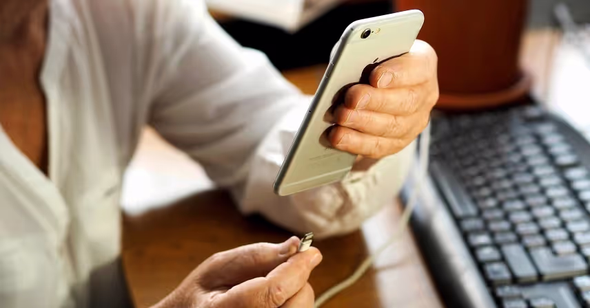 a person holding a phone and putting charger in the port