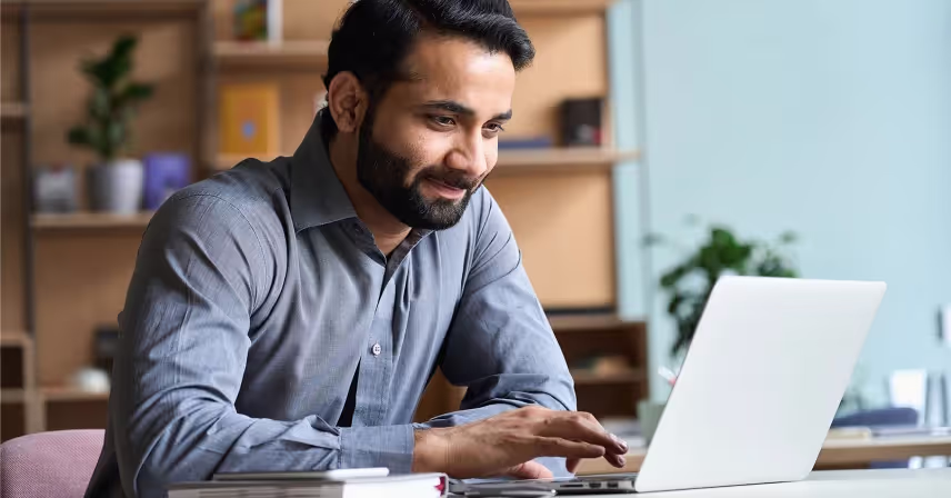 a man smiling while using a laptop