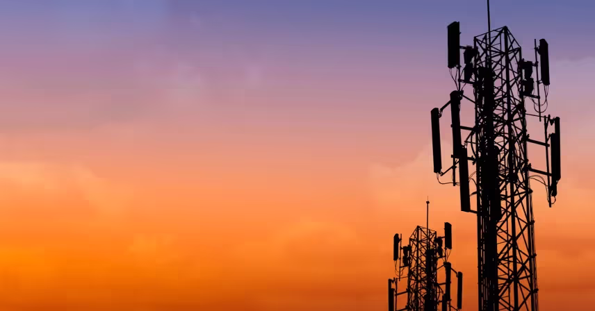 a silhouette of a cell tower with a sunset in the background