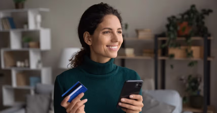 a woman holding a credit card in one and a cell phone in the other