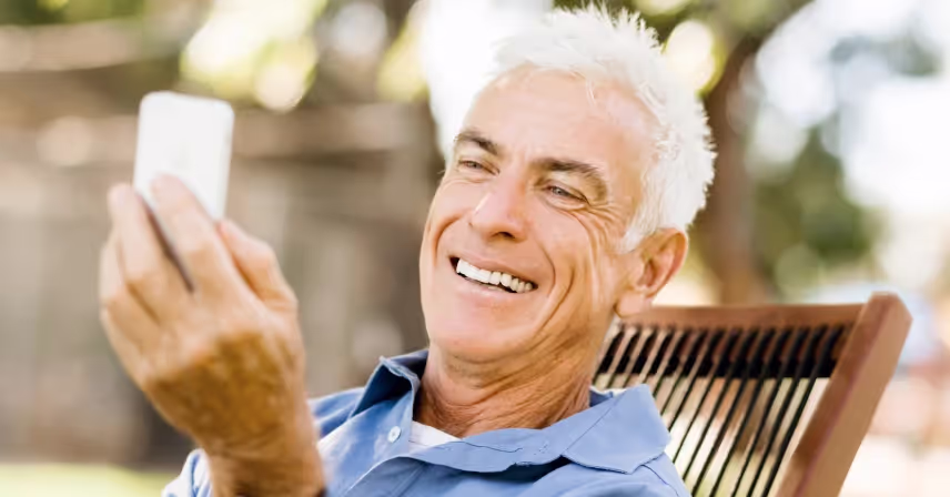 a senior smiling while holding a cell phone