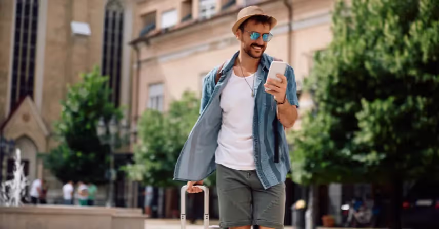 Man with luggage looking at his cell phone