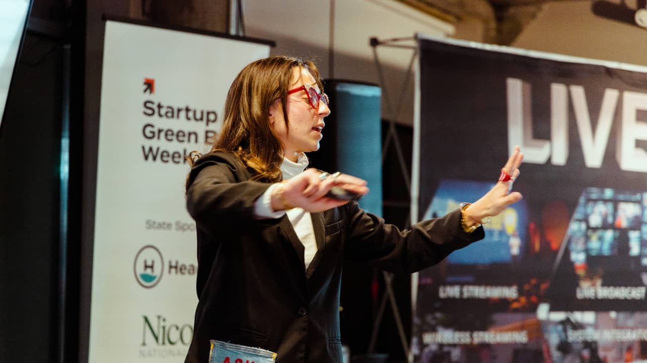 A founder gestures while delivering a pitch on stage at a Northeast Wisconsin pitch competition in Green Bay.