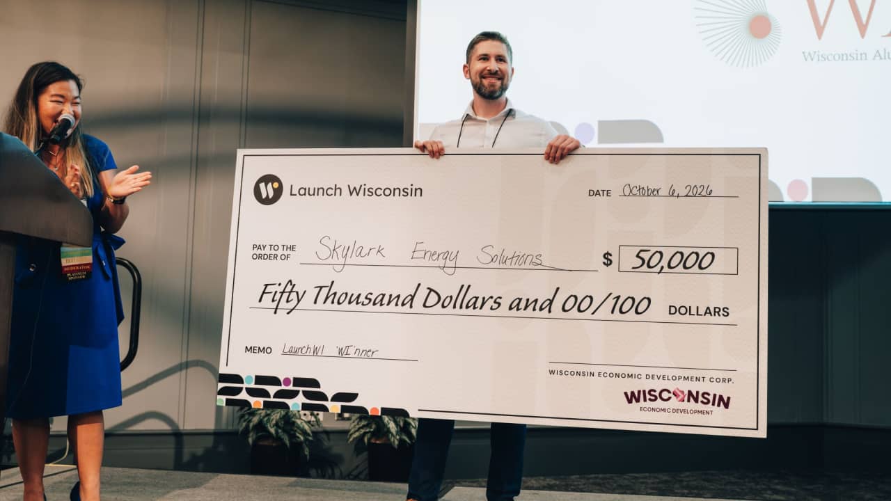 The Skylark Energy Solutions founder holds a $50,000 Launch Wisconsin check on stage at Marquette University, October 6, 2026.