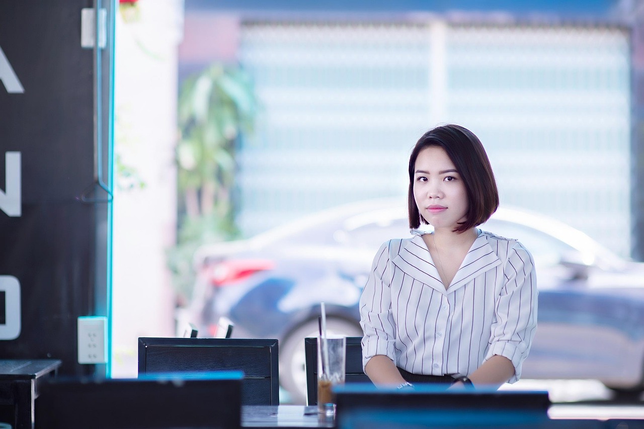 Femme assise au bureau avec expression neutre illustrant l’adaptation du corps malgré des symptômes invisibles