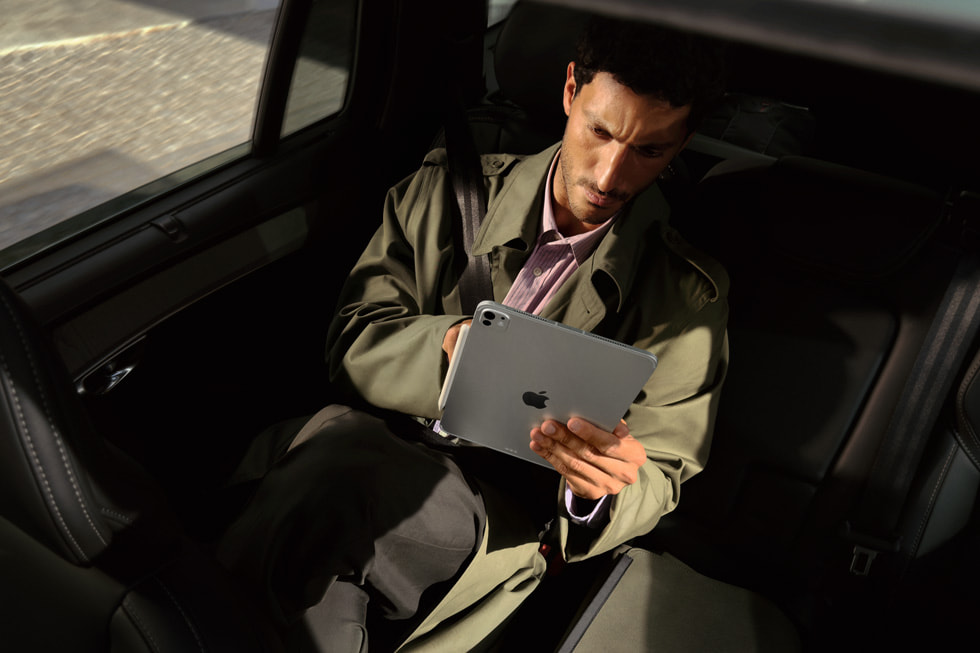 A passenger in the back of a car looks at the new iPad Pro with M5 on the go.