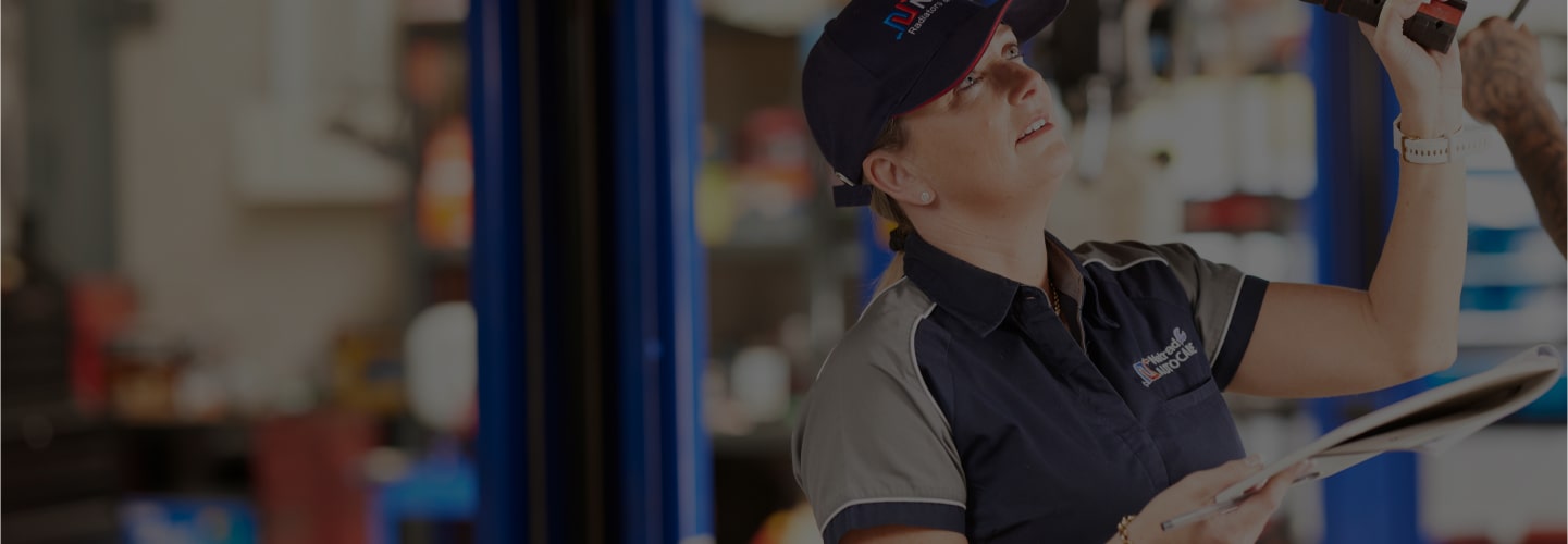 Auto technician in uniform working on vehicle repair at service center