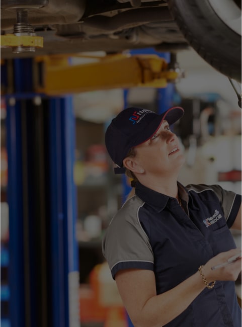 Mechanic looking up under a vehicle on a lift in an auto repair shop