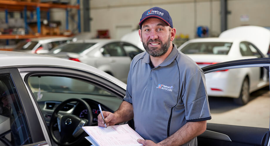 Auto technician filling out paperwork in car repair shop