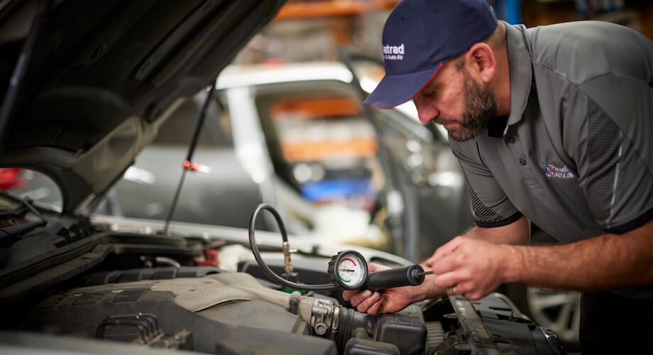 Mechanic checking car engine pressure with diagnostic tool in workshop