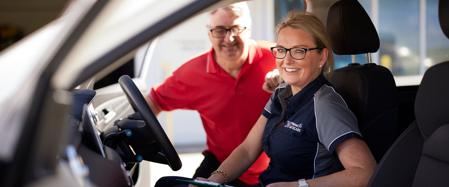Smiling automotive technicians discussing car details in service center