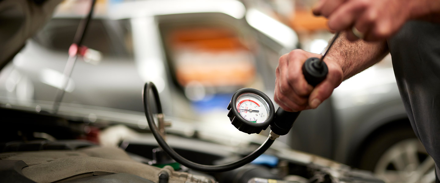 Mechanic checking car tire pressure with pressure gauge