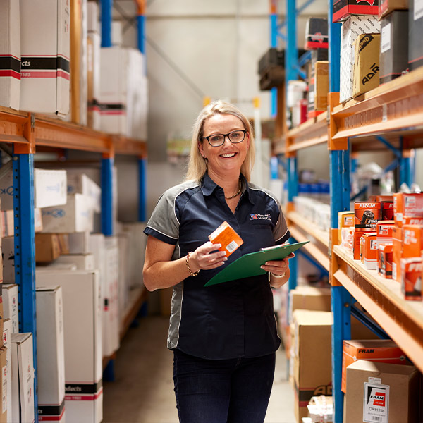 Warehouse worker smiling while checking inventory on shelves