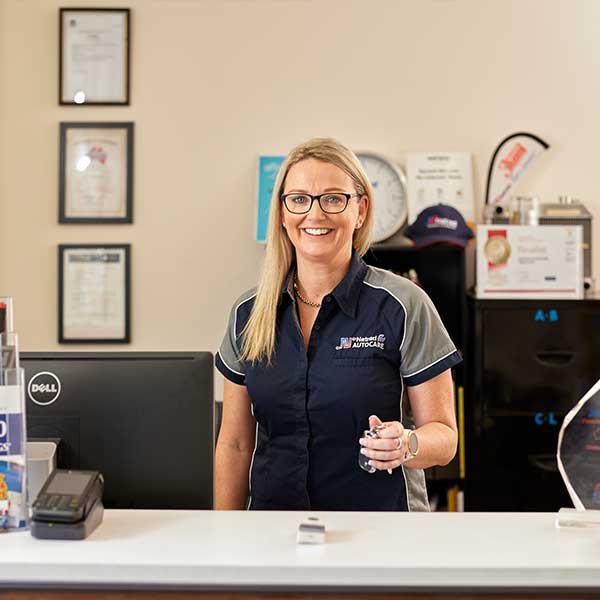 Smiling professional at front desk of automotive business wearing glasses