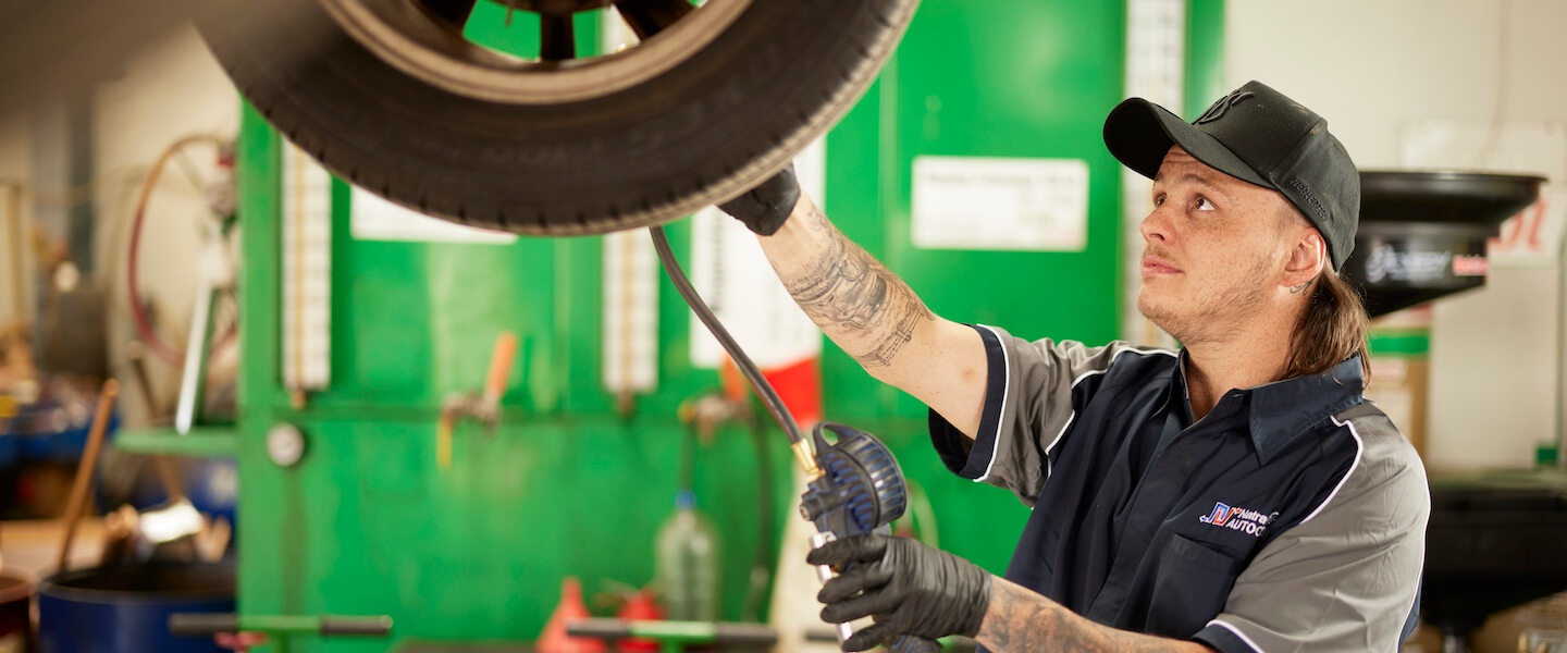 Auto mechanic changing tire on green lift in repair shop