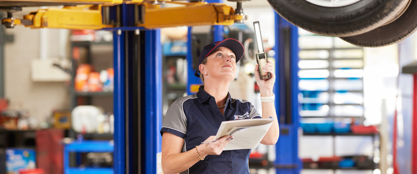 Automotive technician checking equipment in repair shop with clipboard