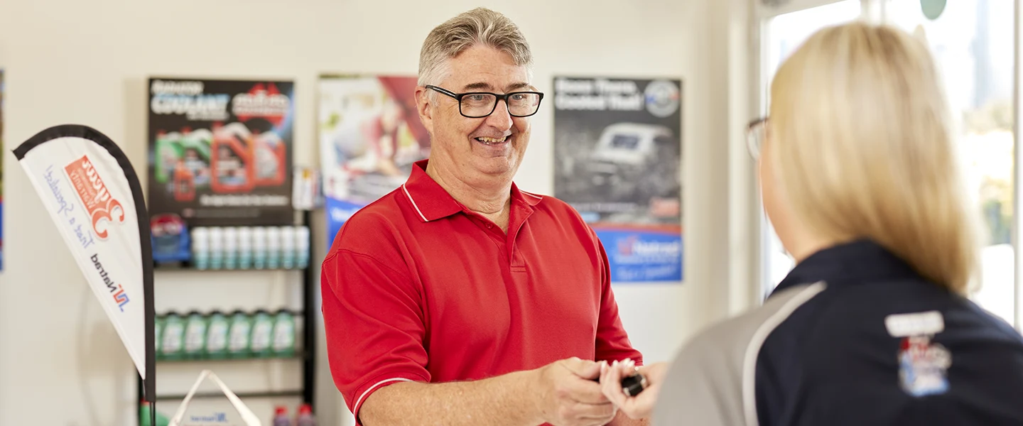 Smiling employee in red shirt working at automotive service center
