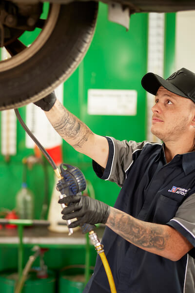 Auto mechanic checking tire pressure in green automotive repair shop