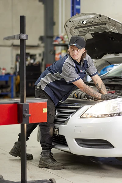 Mechanic inspecting car engine in automotive repair shop
